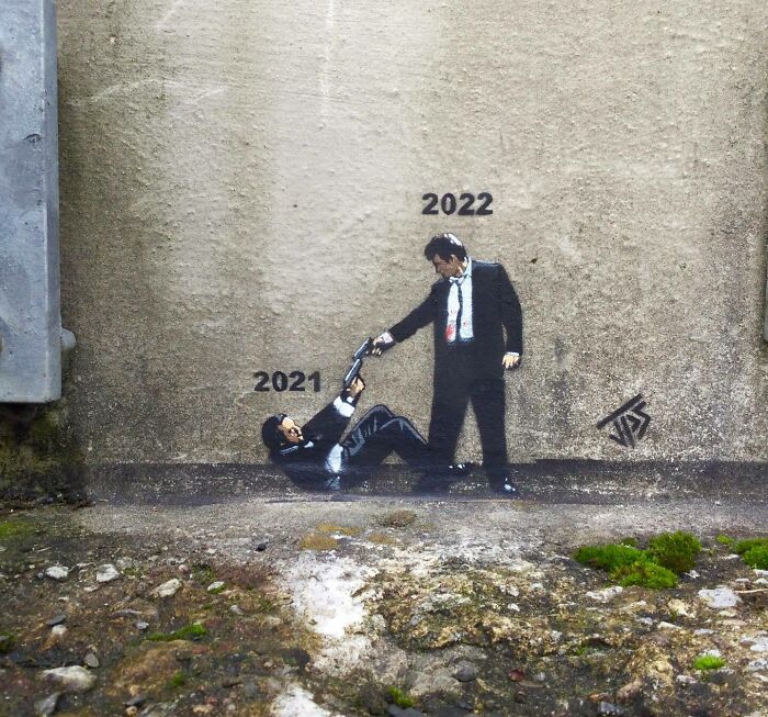 Graffiti street art showing 2022 helping 2021 in an interactive mural blending with the urban surroundings.