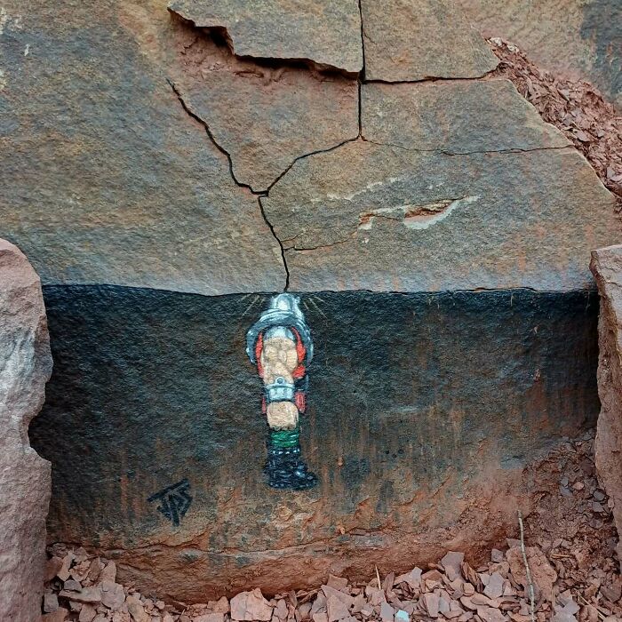 Graffiti artist creates street art interacting with natural rock surroundings, blending vibrant colors and textures creatively.