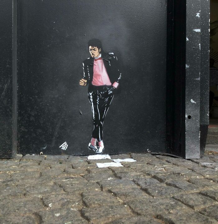 Street art graffiti of a dancing figure interacting with cobblestone street, enhancing surroundings creatively.