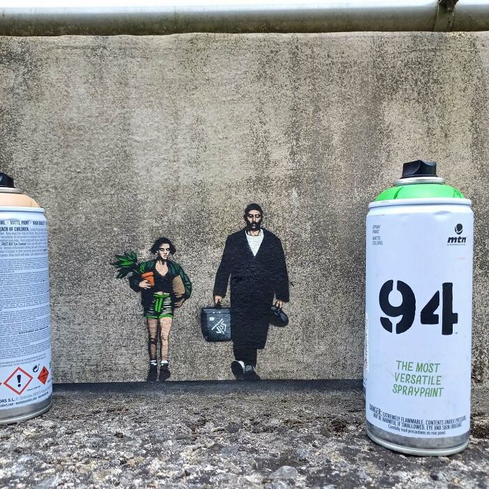 Creative graffiti art interacts with spray paint cans on the street, making urban surroundings more engaging and visually dynamic.