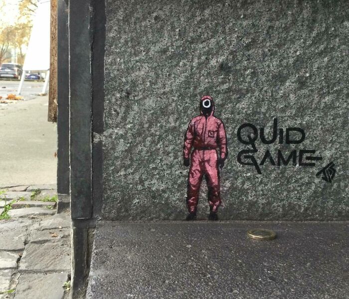 Graffiti street art inspired by Squid Game character interacting with urban surroundings on a stone wall corner.