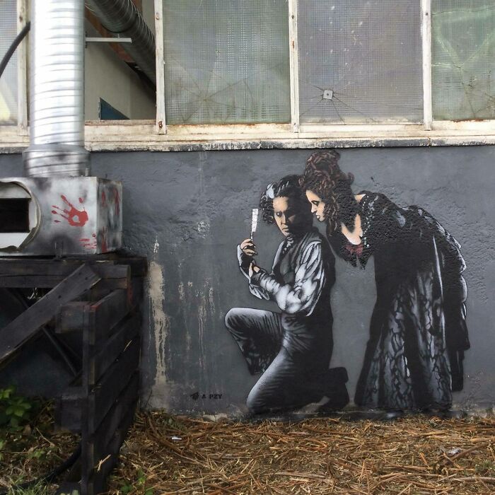 Graffiti art interacting with surroundings shows two people in vintage clothing near industrial wall and vent.