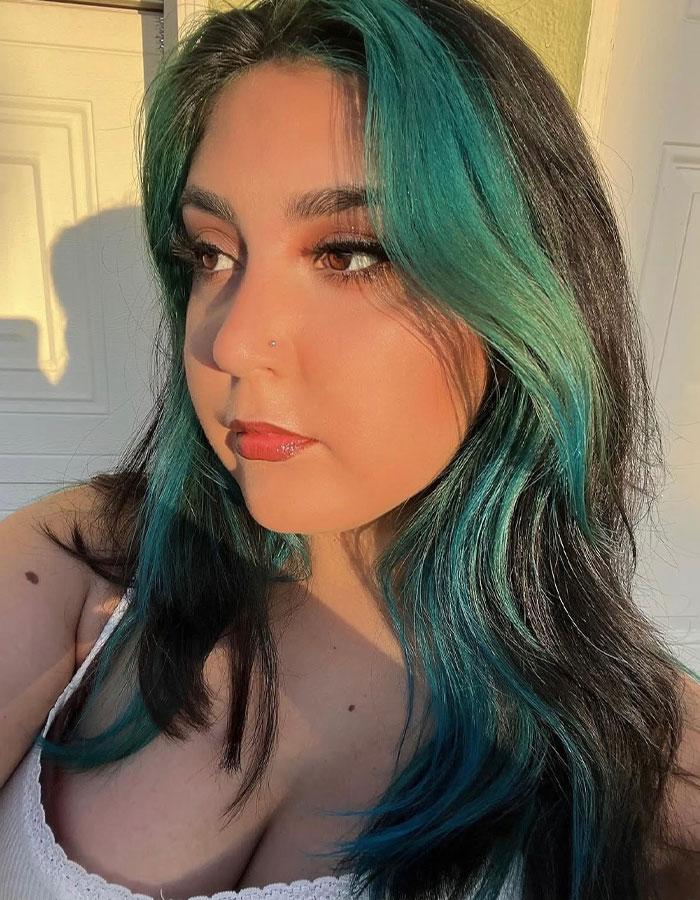 Young woman with teal and black hair, posing in natural sunlight, relating to horrific 7-Eleven manager roommate story