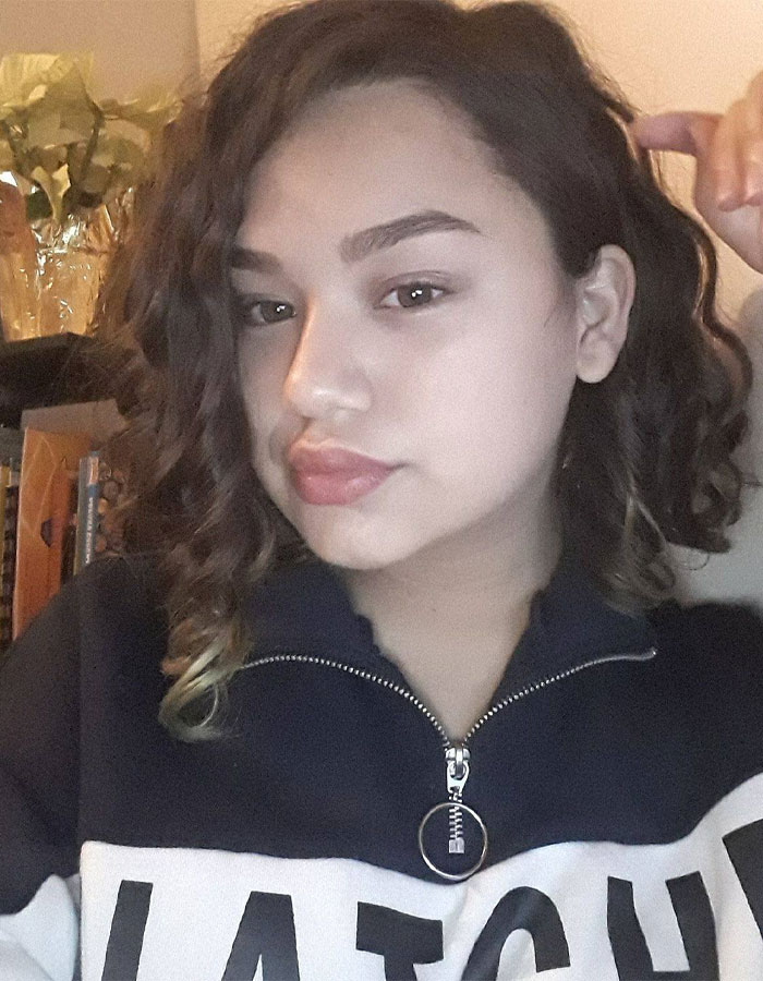 Young woman with curly hair wearing a black and white zip-up jacket, related to 7-Eleven manager and horrific coworker incident.