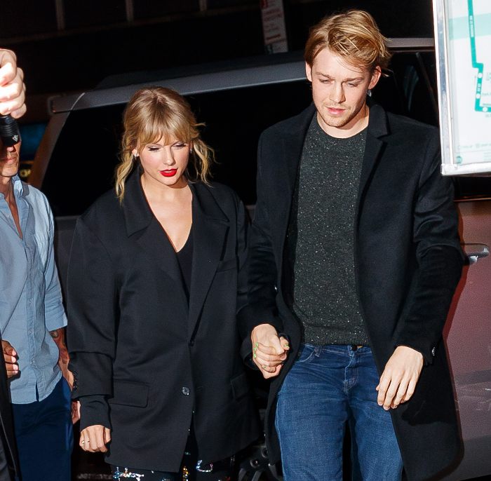 Taylor Swift and Travis Kelce holding hands at night, showcasing body language that stands out among past loves.