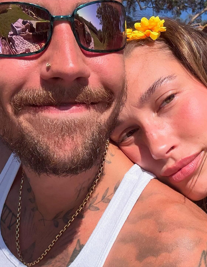 Justin Bieber and Kendall Jenner close-up selfie outdoors with bright sunlight and a flower in her hair.