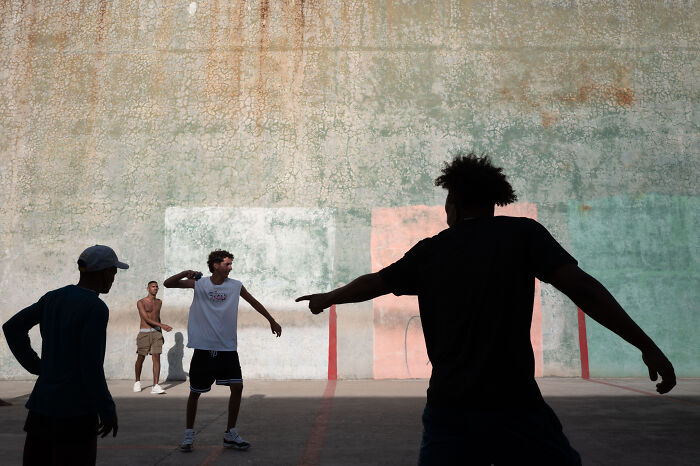 Group of young men playing basketball on an urban court, capturing the beauty of ordinary life in street photography style.