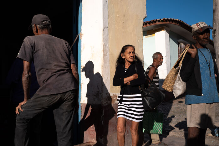 Group of people on a sunny street corner captured by street photographer highlighting ordinary life and everyday moments.
