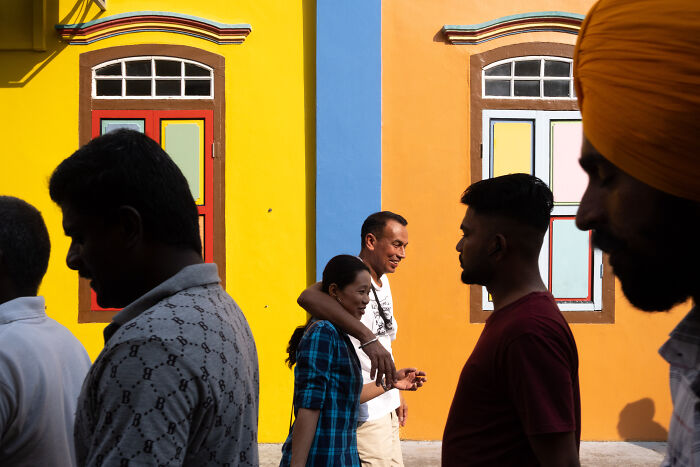 People walking in front of colorful buildings, showcasing street photographer capturing beauty of ordinary life.