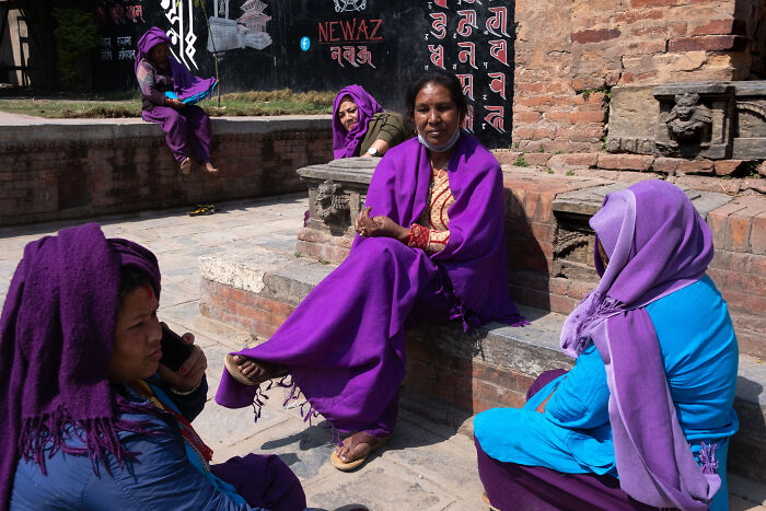 Street photographer captures vibrant scene of women in traditional attire embracing ordinary life in a historic outdoor setting.