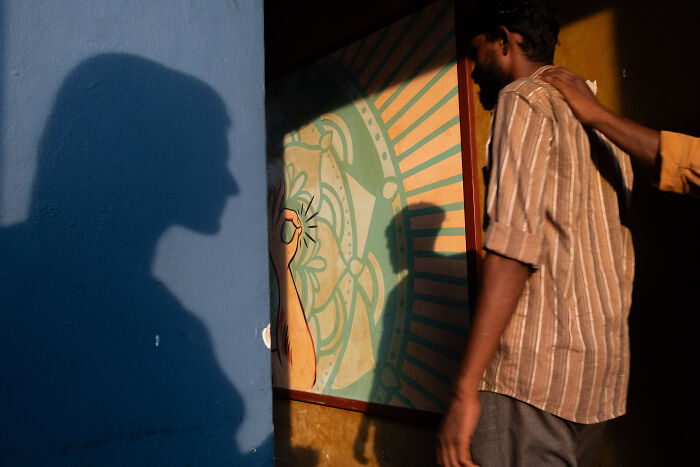Man walking near colorful wall with shadow of face, capturing street photographer’s beauty of ordinary life moment.