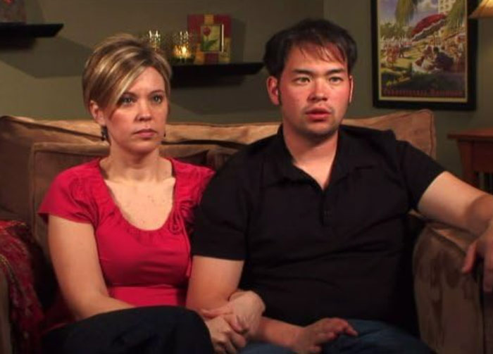 Reality star Kate Gosselin sitting with a man on a couch, looking serious amid nursing career news.