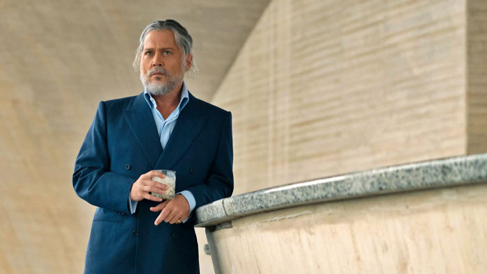 Man in a navy blazer holding a glass, representing AI transforming Keanu Reeves into Jack Sparrow for Johnny Depp fans