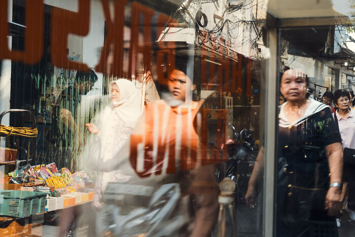 Street scene with blurred pedestrians and market stalls, showcasing poetic cinematic photography of ordinary moments.
