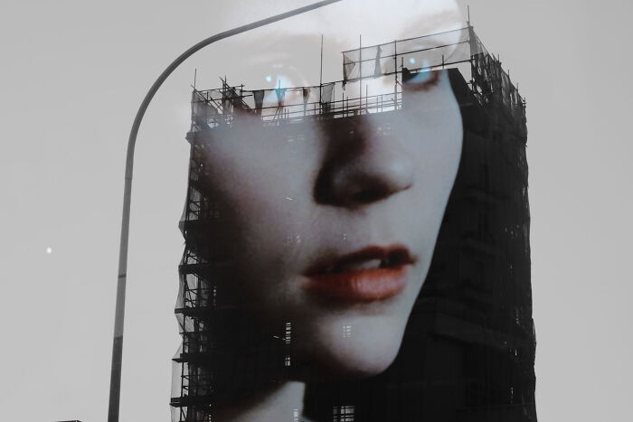 Double exposure image blending a woman's face with a building under construction, showcasing poetic, cinematic photography style.