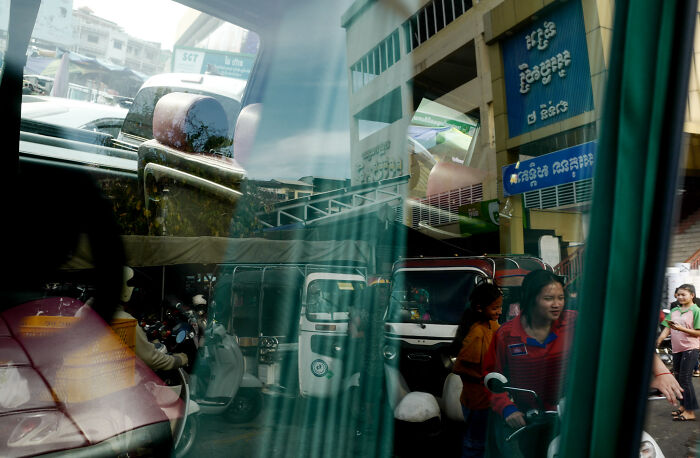 Reflection of busy urban street scene captured by a photographer turning ordinary moments into poetic cinematic images.