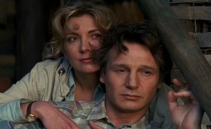 Liam Neeson with a woman resting behind him, portraying a contemplative moment related to rumored romance with Pamela Anderson. - 8