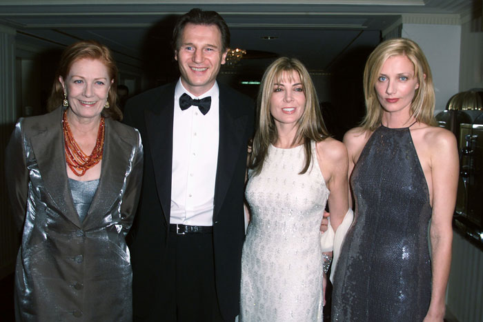Liam Neeson smiling with three women at a formal event, related to his late wife's sister and rumored romance news. - 1