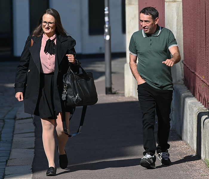 Person who changed gender after conviction walking outside with another individual on a sunny day.