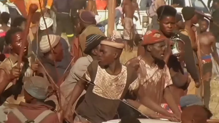 Group of men in traditional attire participating in a mass circumcision ceremony with many boys involved in the ritual. - 7