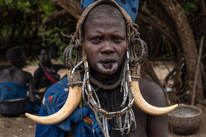 Portrait of a person from a traditional culture wearing tribal jewelry and large tusk ornaments, showcasing cultural beauty.