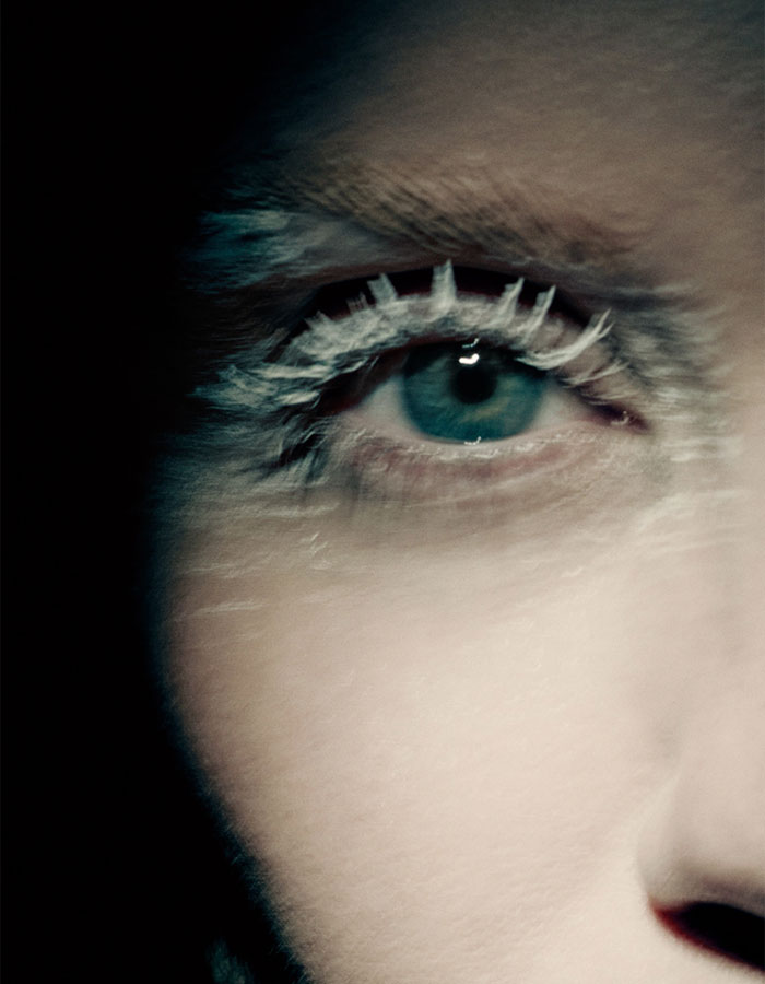 Close-up of an eye with white body paint lashes in Miley Cyrus' body paint campaign for Maison Margiela.