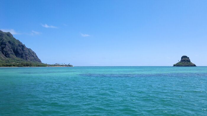 Ocean view with clear blue water and distant island, evoking the serenity of some of the world’s greatest unsolved mysteries.