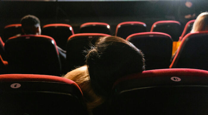 Audience sitting in a dark theater watching a presentation, relating to the moral dilemma poll topic.