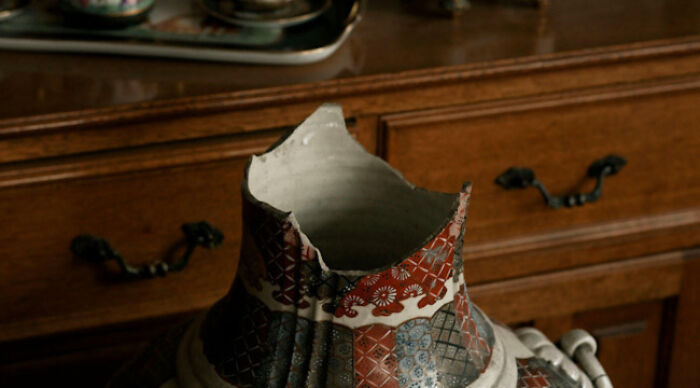 Broken patterned ceramic vase on a wooden surface, symbolizing reflection in moral dilemma and am I the problem concept.