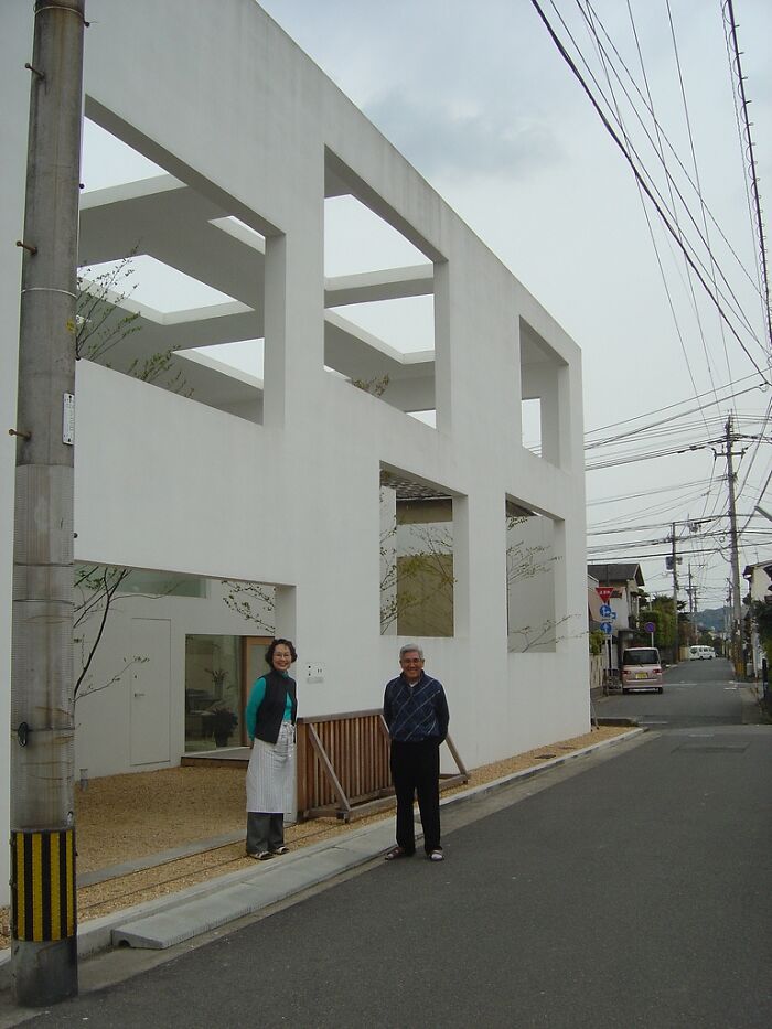 Modern Iconic architectural homes with minimalistic white concrete design and large geometric window openings on a city street.