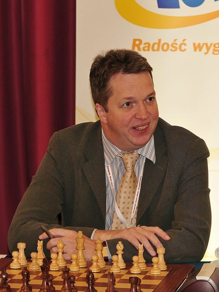 Man in a suit playing chess at a board, representing the smartest kids and their intellectual pursuits.