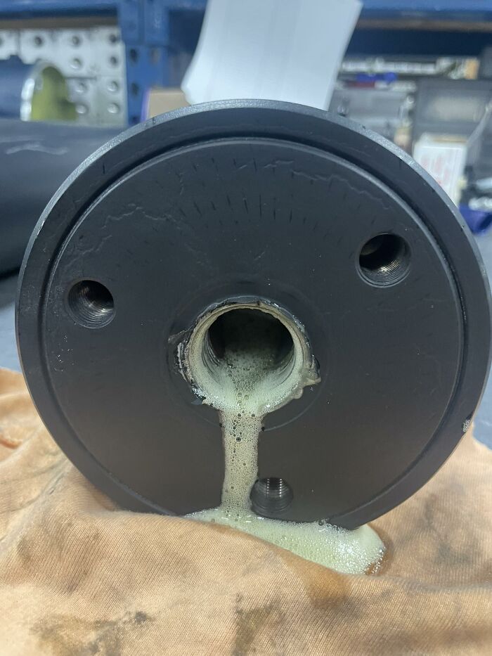 Black cylindrical object leaking foam that resembles a face with eyes and a mouth, posted in random objects looking like faces group.