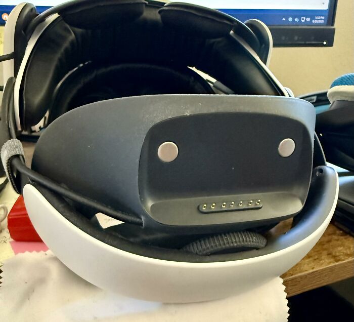 VR headset on a desk showing a face-like arrangement of buttons and screws, a random object resembling a face.