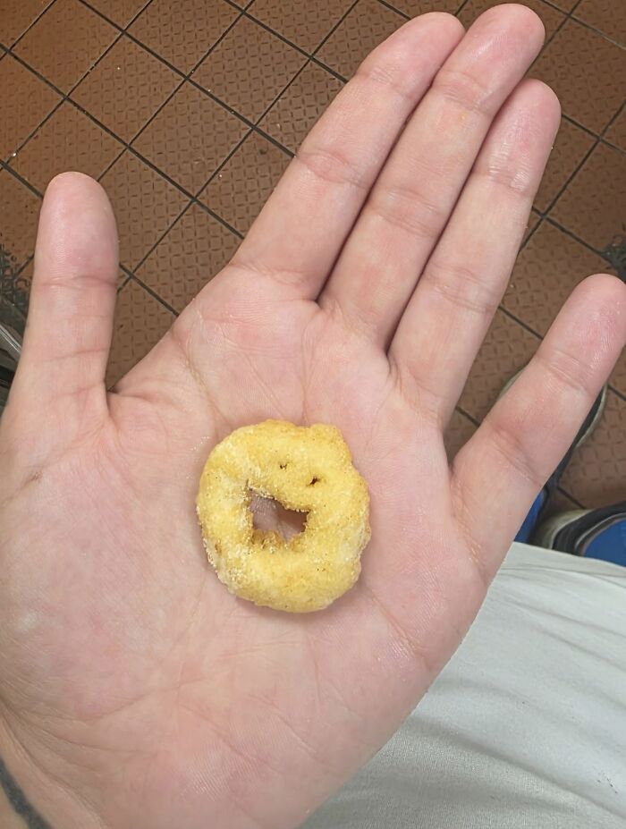 Small snack resembling a smiling face held in an open hand, showcasing random objects that look like faces.