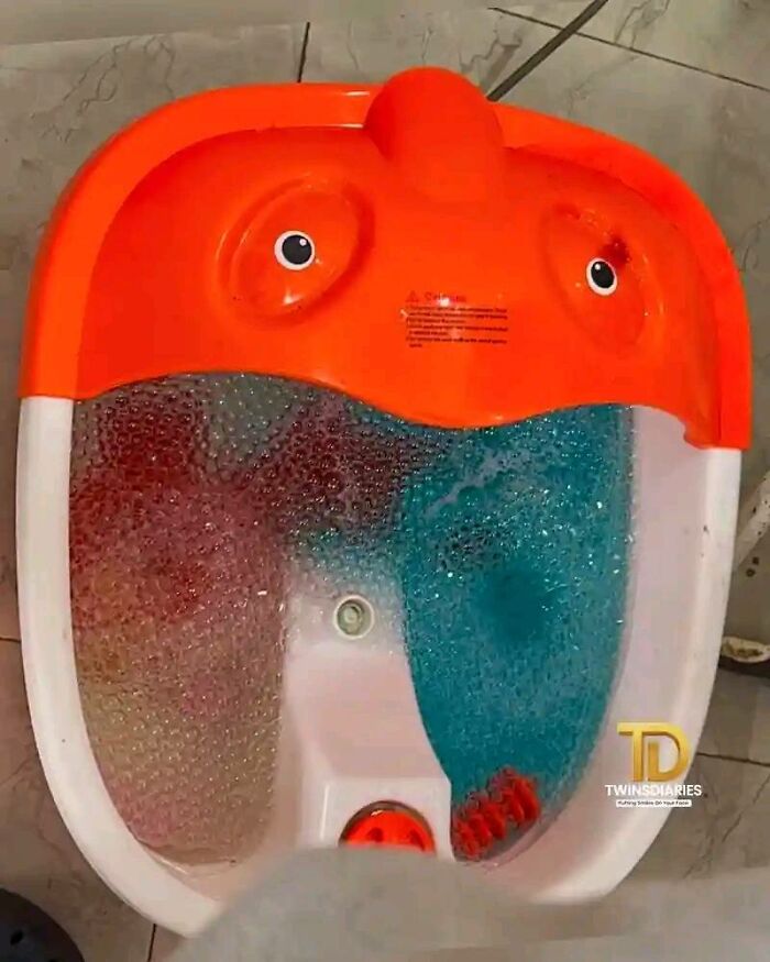 Orange and white foot spa with bubbles and stickers resembling eyes, creating a random object that looks like a face.