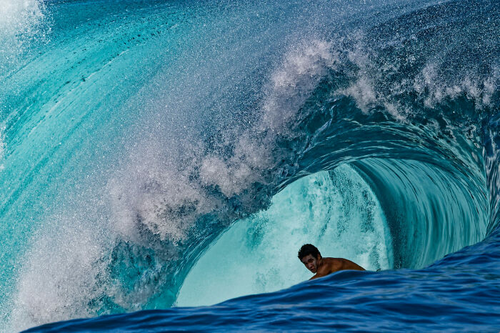 Surfer riding inside a powerful wave, captured in a stunning ocean photographer of the year awards image 2025.
