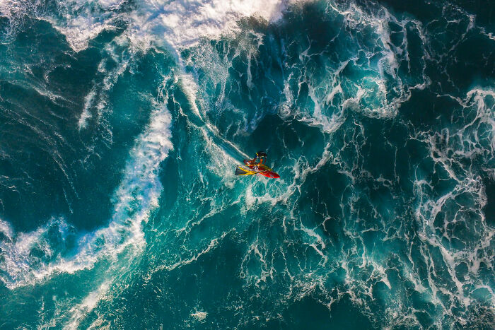 Kayaker navigating powerful ocean waves in stunning image from 2025 Ocean Photographer of the Year Awards.
