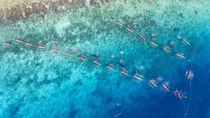Aerial view of traditional boats floating on clear blue ocean water showcasing stunning ocean photography.