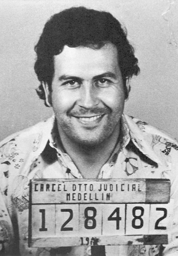 Black and white mugshot of a notorious mob boss smiling, holding a sign from Medellin judicial prison.