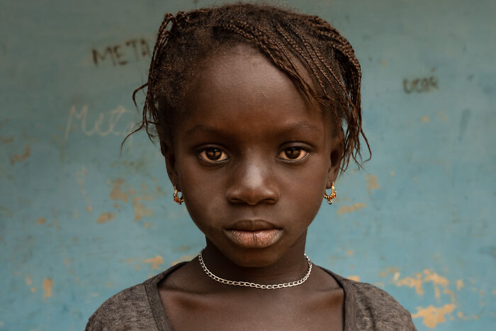 Portrait of a young girl with braided hair and hoop earrings, showcasing cultural beauty captured by a world-traveling photographer