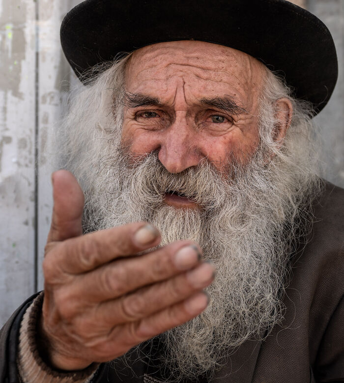 Close-up of an elderly man with a long beard and hat, showcasing the beauty of cultures captured by a photographer.