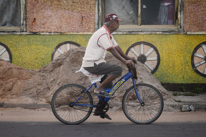 Man riding a bicycle on a street with colorful wall art, showcasing the beauty of cultures in travel photography.