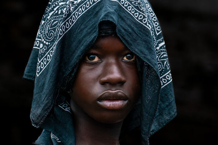 Close-up portrait of a young person wearing a patterned headscarf, showcasing cultural beauty captured by photographer.