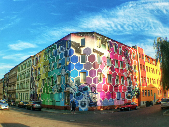 Colorful street art mural covering an entire building corner, showcasing vibrant hexagon patterns and artistic designs.