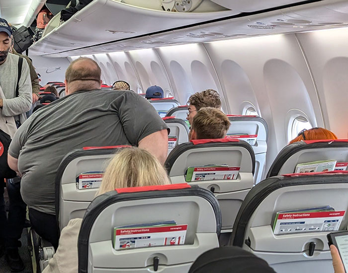 Plus-size passenger struggling to fit in airplane seat amid controversial airline rule and passenger reactions inside the cabin. Plus-size passenger struggling to fit in airplane seat amid controversial airline rule and passenger reactions inside the cabin.