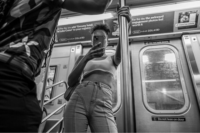 Black and white photograph of a woman capturing the hidden poetry of everyday life on a subway train.