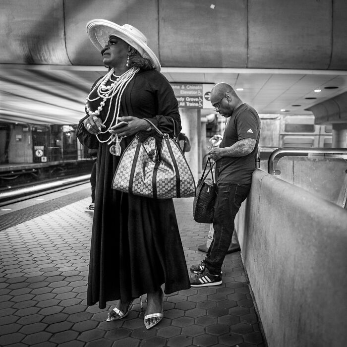 Black and white photograph capturing the hidden poetry of everyday life with stylish people waiting at a metro station.