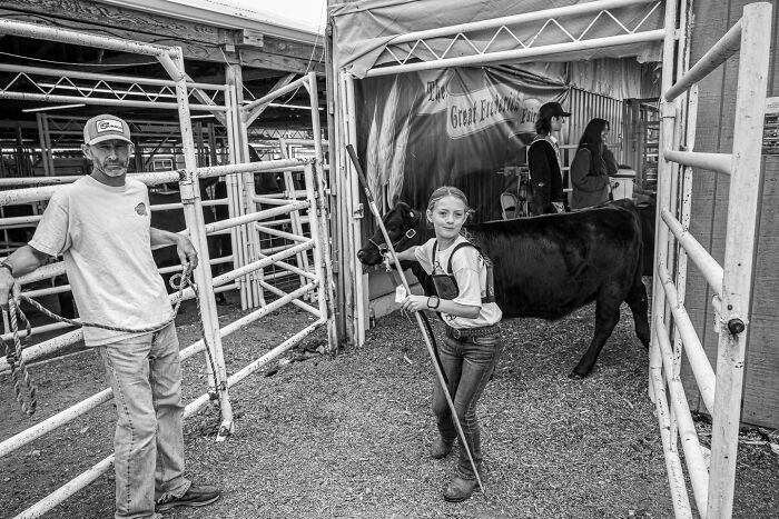 Black and white photograph of a young girl and man with a cow, capturing the hidden poetry of everyday life moments.