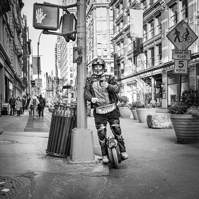 Urban street scene featuring a person on a unicycle, capturing the hidden poetry of everyday life in black and white.