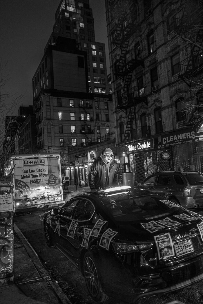 Man in a hooded jacket standing on a city street at night, captured in striking photographs revealing hidden poetry.